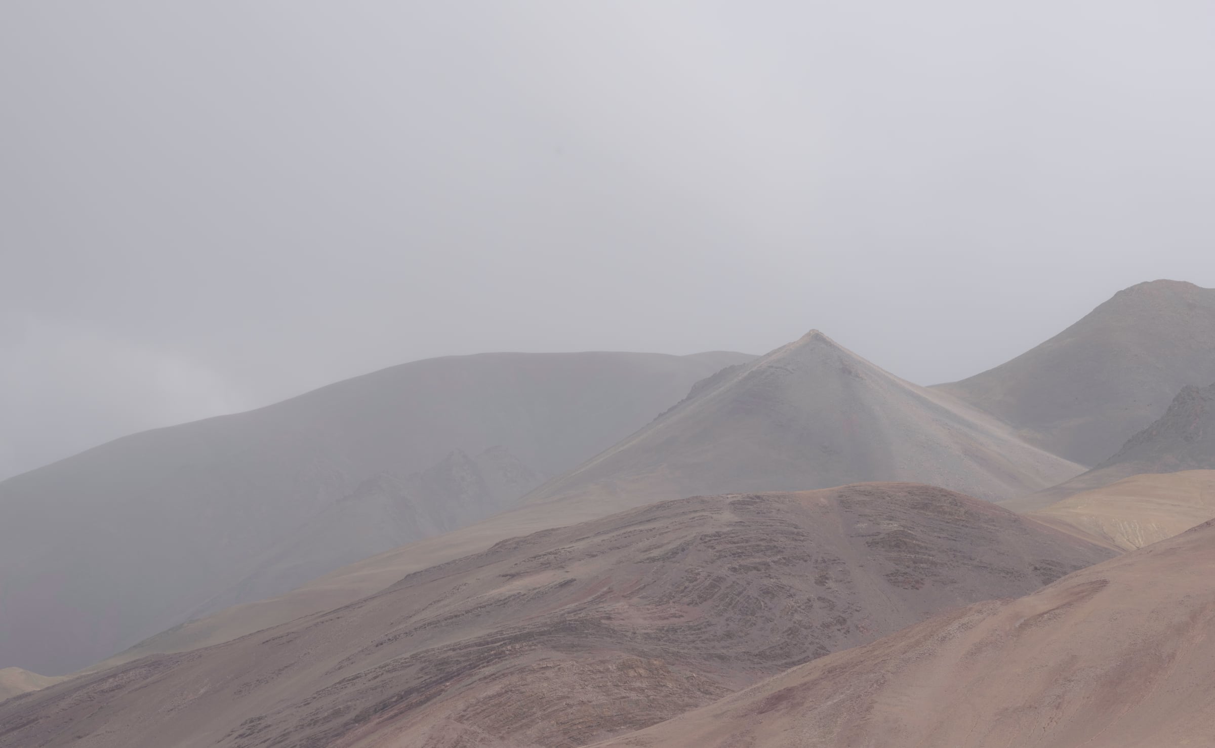 Hazy brown mountain ridges beneath an overcast sky