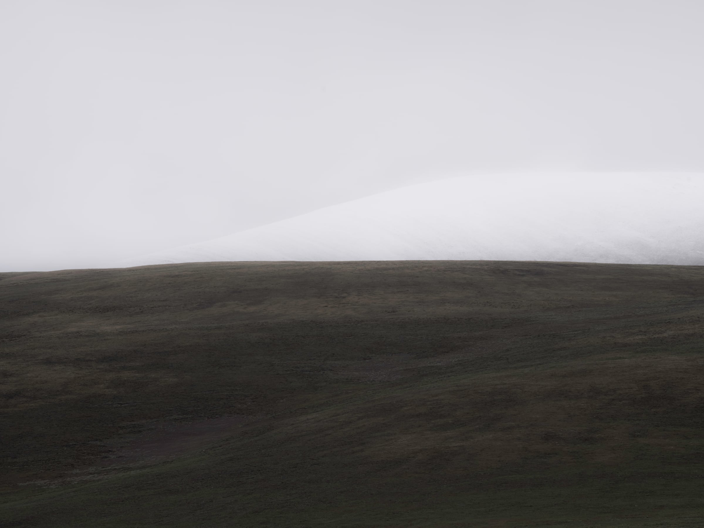 A low dark ridge beneath a band of white cloud
