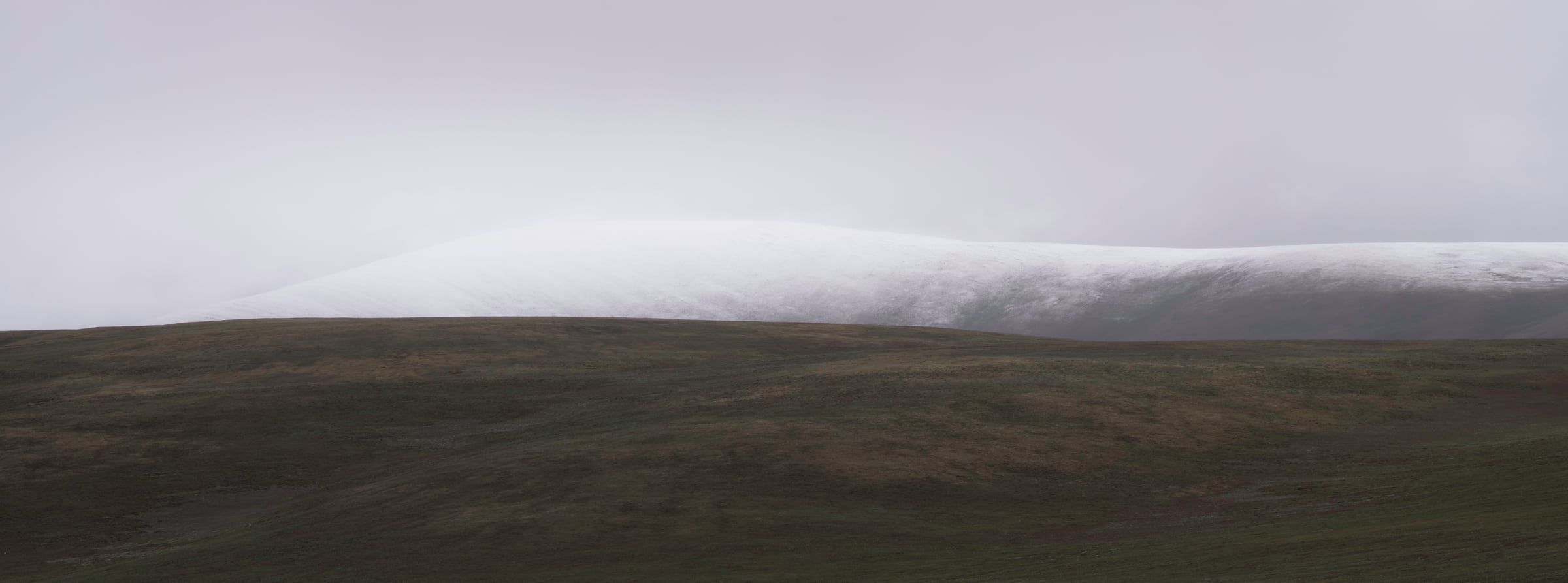 A long white cloud resting above a dark ridge