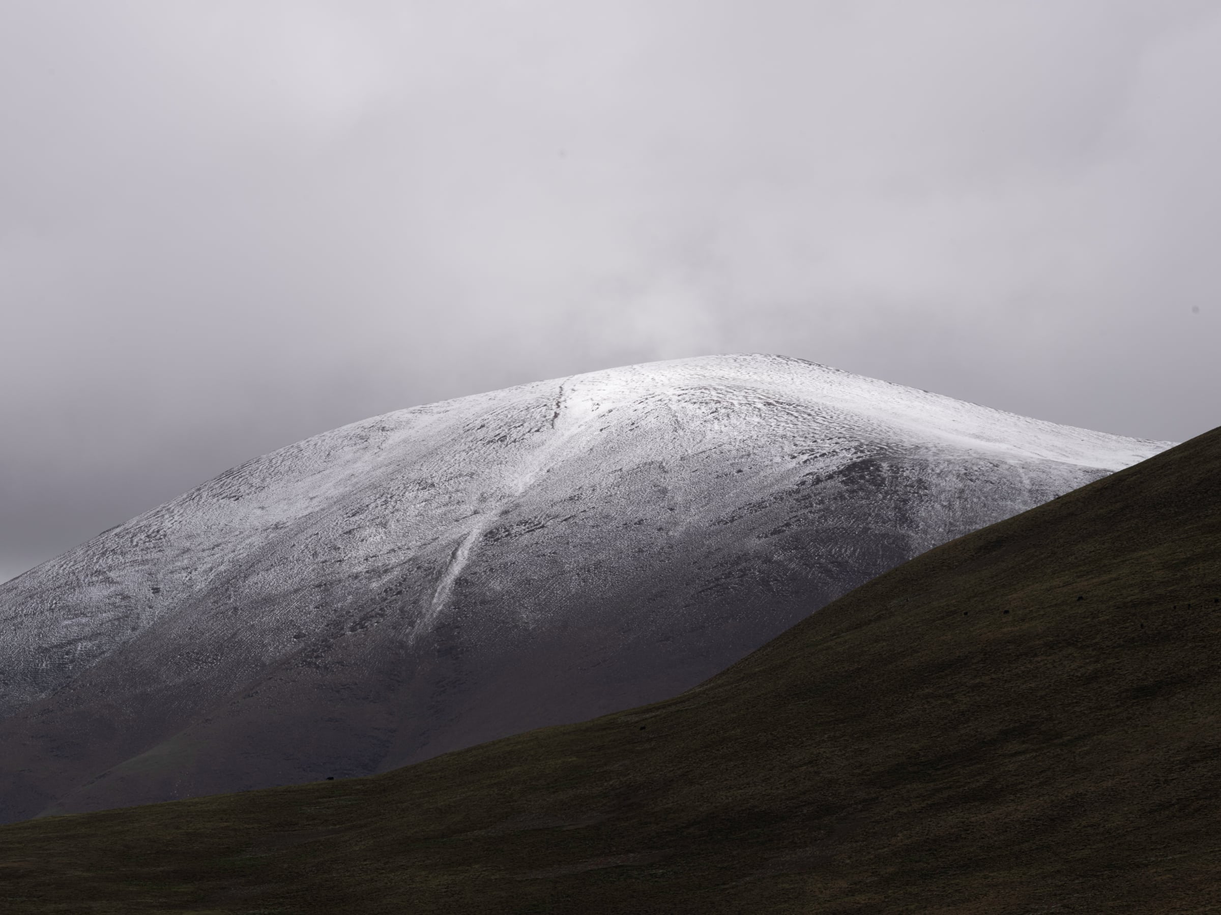 A snow-dusted mountain ridge behind a dark slope