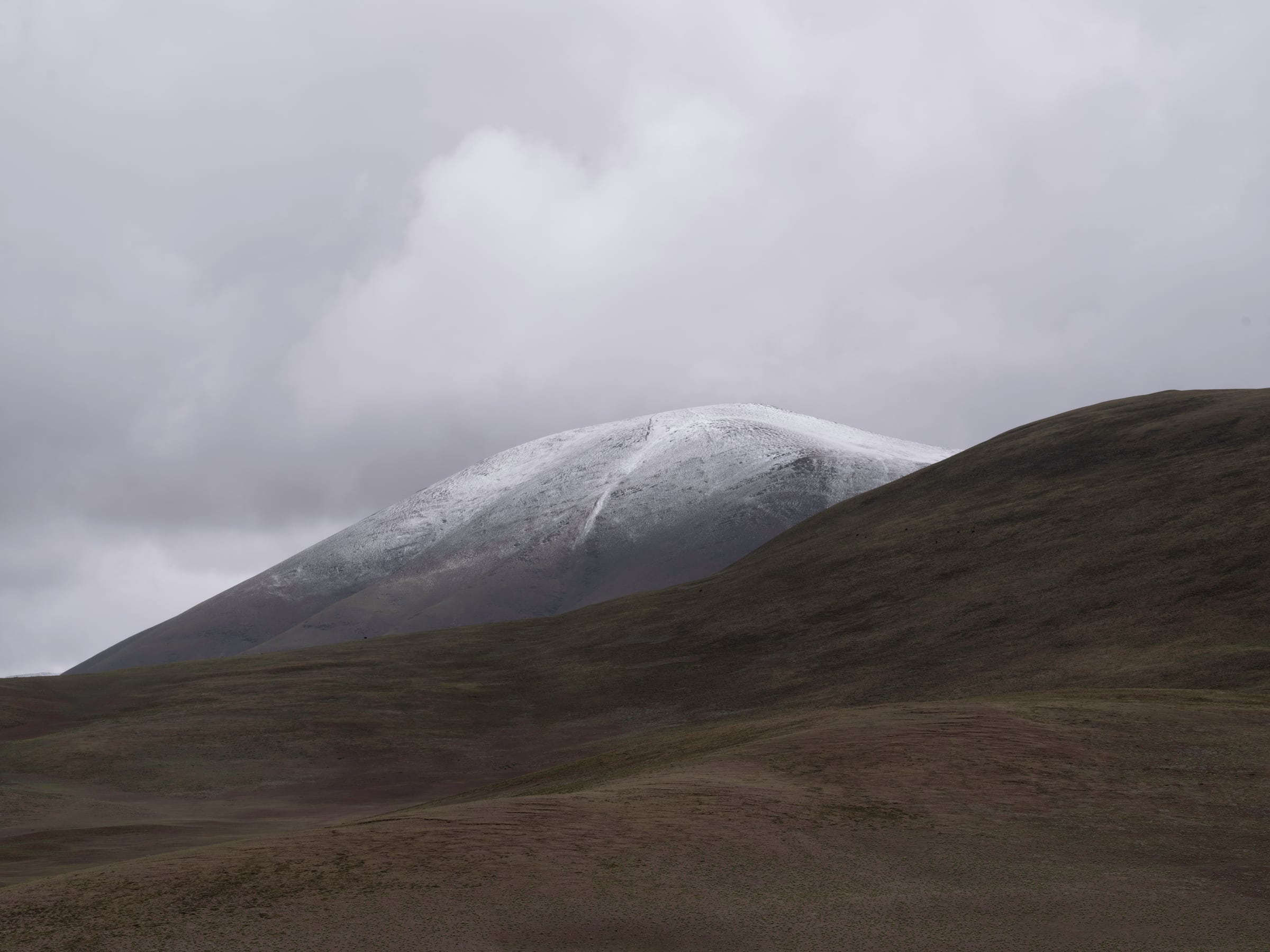 A snow-covered ridge below a cloudy sky